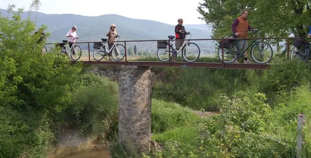 Eine Gruppe von Radfahrern, die eine schmale Brücke schiebend überqueren