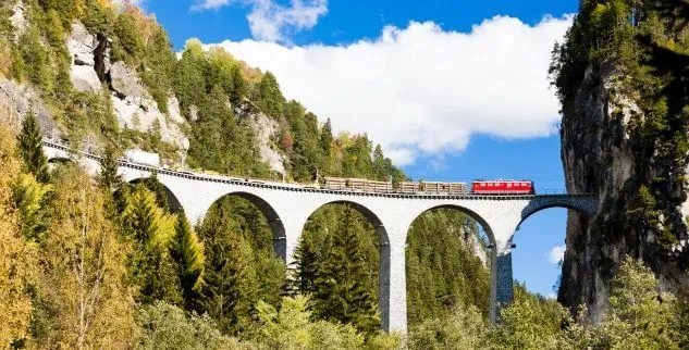 Zug auf Brücke zwischen zwei Alpengipfeln